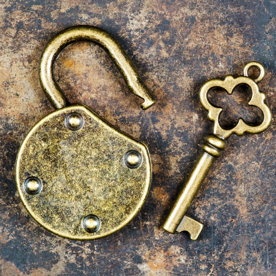 Geöffnetes goldenes Vorhängeschloss mit passendem Schlüssel auf rostigem Hintergrund – Symbol für VitalEscapeGames