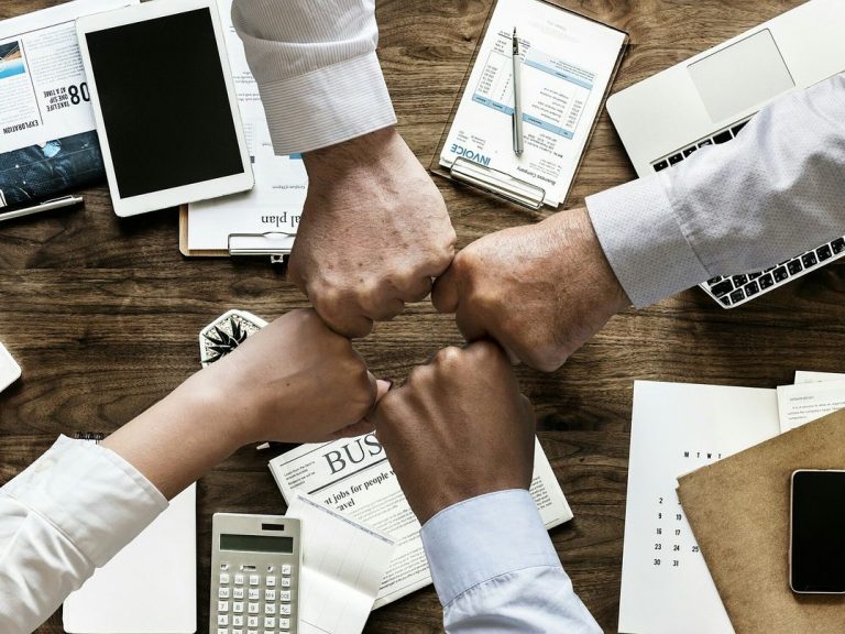 Hände mehrerer Personen greifen ineinander – Symbol für Zusammenarbeit